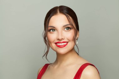 Güzel genç bir kadın beyaz arka planda gülümsüyor.