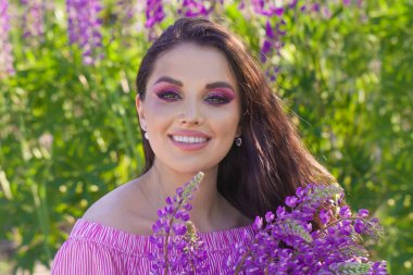 Açık havada gülümseyen renkli yaz çiçekleriyle güzel bir kadın.