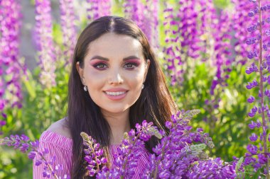 Açık havada renkli yaz çiçekleri olan mutlu genç bir kadın.