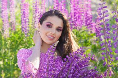 Açık havada renkli yaz çiçekleri olan esmer bir kadın.