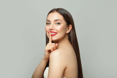 Dudaklarının yanında parmağını tutan mutlu genç bir kadın. Gizli ve sessiz kavram