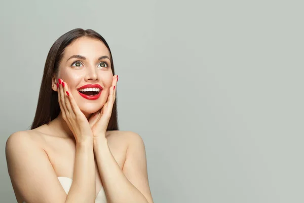 Happy surprised woman with red manicured nails on hands on white banner background