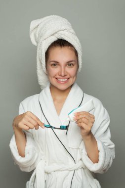 Gülümseyen spa kadını diş macunuyla dişlerini fırçalıyor.