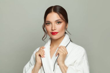 Beyaz arka planda beyaz bornozlu güzel kadın.