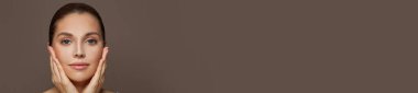 Mükemmel bir genç kadın yüzü, açık tenli kahverengi afiş arkaplanlı, kopya alanı olan.
