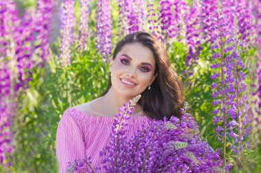 Açık havada çiçeklerle gülümseyen güzel bir kadının yaz portresi.