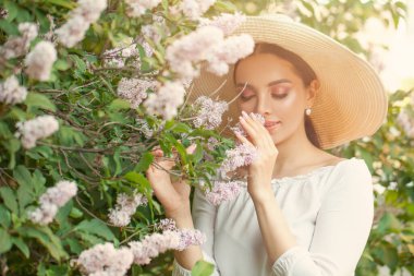 Genç ve güzel bir kadın bahar çiçeklerini kokluyor.