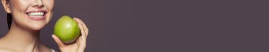 Beyaz dişli, güzel kadın gülüşü ve kahverengi pankartta yeşil elma