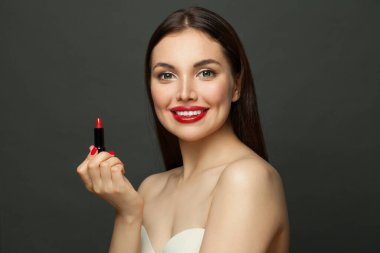 Çekici model kadın siyah arka planda dudaklarına ruj sürüyor.