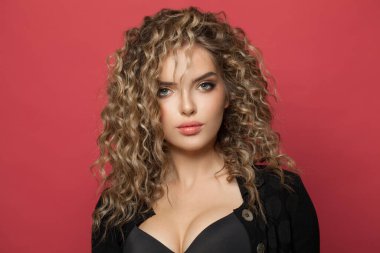 Kırmızı arka planda uzun kıvırcık saçlı, mükemmel bir kadın. Moda tarzlı ve saç boyalı güzel bir model.