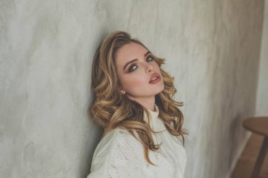 Gri sıva duvarının yanında poz veren çekici kadın.