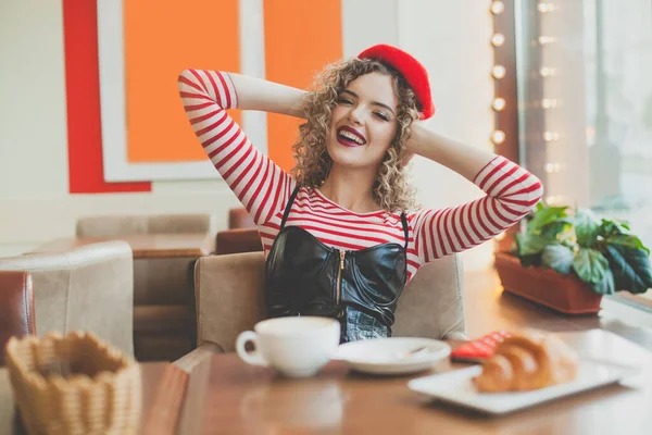 若いです可愛いです女性で赤ベレー帽でフランス料理の朝食でコーヒーとクロワッサン座ってカフェ — ストック写真