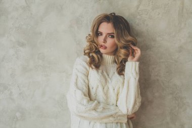 Gri arka planda sağlıklı kıvırcık saçlı şık bir kadın.