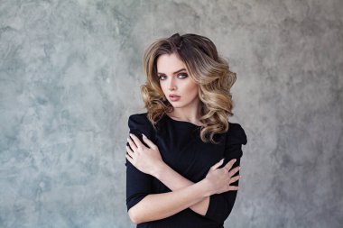Gri kaplama arka planda kıvırcık saçlı mükemmel kadın modelinin moda portresi.