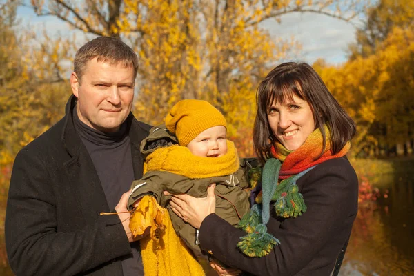 屋外の秋の公園で本当の笑顔の家族の肖像画 お母さん お父さんと赤ちゃんは屋外で一緒に楽しんでいます — ストック写真