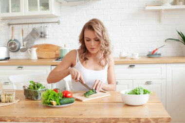 Genç bir kadın mutfağında sebze salatası hazırlıyor. Sağlıklı yaşam tarzı kavramı. Karışık sebzeli güzel kadın.