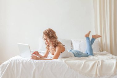 Kanepede rahat bir kadın olarak sırt üstü bilgisayarı kullanmak çok önemli. Evde dizüstü bilgisayarla kanepede yatan genç kadının portresi. 