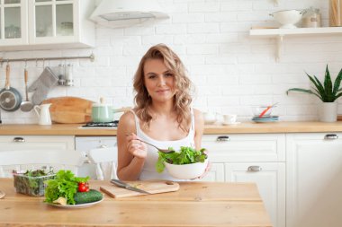 Salata yiyen bir kadın. Güzel, sağlıklı, gülümseyen kadın taze, sağlıklı salatanın tadını çıkarıyor.