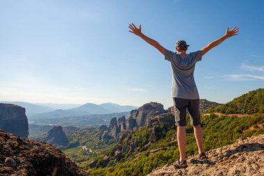 Dağa ve gökyüzüne tepeden bakan ve tatilin tadını çıkaran genç adam.