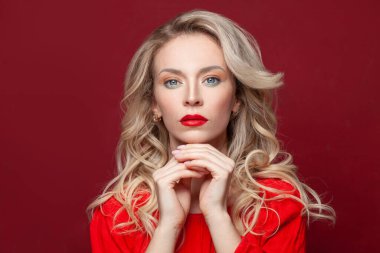 Güzel olgun sarışın kadın yüzü. Makyajlı ve kırmızı pankartta sağlıklı kıvırcık saçlı bir kadın model.