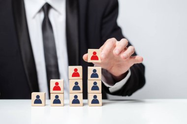 İş adamı eli, tahta küpün üstüne insan ikonu koyuyor. İş stratejisi, eylem planı, ortaklık ve takım kavramı.