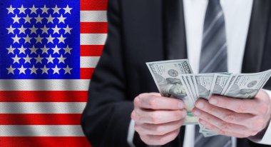 Ulusal Amerikan bayrağı arkaplanındaki erkeklerin elinde dolar banknotları.