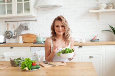 Evde yeşil sebze salatası yiyen sağlıklı bir kadın.