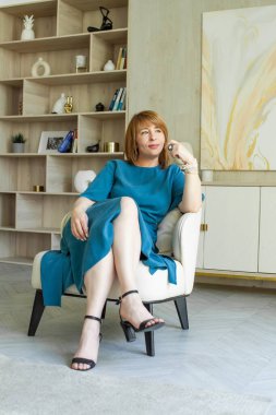 Olumlu iyimser orta yaşlı kadın güler yüzlü ve koltukta oturur.