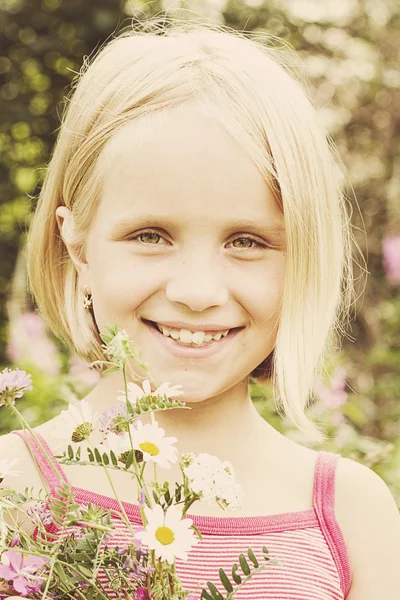 Vrolijk meisje met wild zomerbloemen buitenshuis — Stockfoto