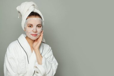 Çarşaf maskesi takan çekici bir kadın. Cilt bakımı ve hidrasyon konsepti