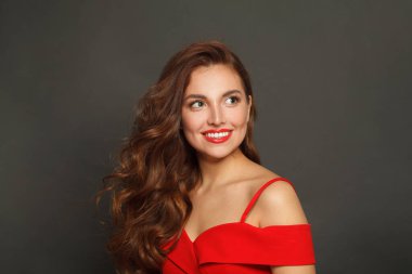 Siyah arka planda uzun saçlı ve makyajlı bir kadın. Kıvırcık saçlı, güzel bir kadın.