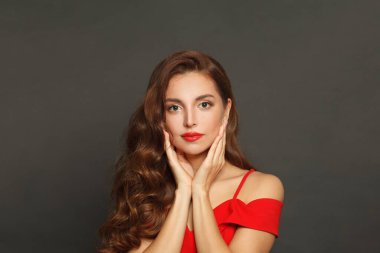 Siyah arka planda uzun saçlı ve makyajlı çekici bir kadın. Kıvırcık saçlı, güzel bir kadın.