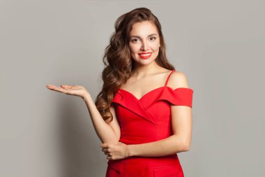 Boş avuç içini tutan ve beyaz arka planda kameraya bakan kendine güvenen bir kadın.