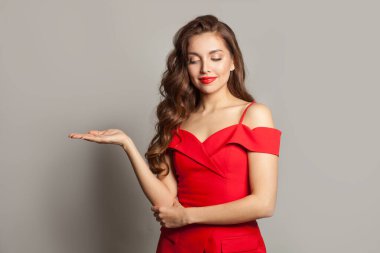 Güzel model kadın boş avuç içini tutuyor ve beyaz arka planda gülümsüyor.