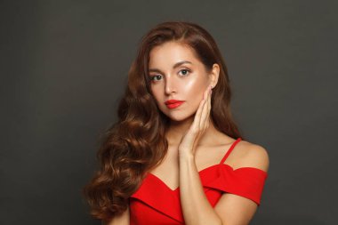 Siyah arka planda uzun saçlı ve makyajlı muhteşem bir kadın. Kıvırcık saçlı, güzel bir kadın.