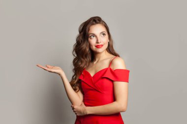 Neşeli model kadın boş avuç içini tutuyor ve beyaz arka plana bakıyor.