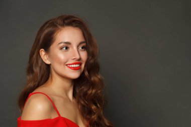 Siyah arka planda uzun saçlı ve makyajlı neşeli bir kadın. Kıvırcık saçlı, güzel bir kadın.