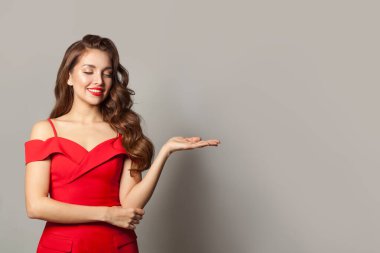 Çekici model kadın boş avuç içini tutuyor ve beyaz arka planda gülümsüyor.