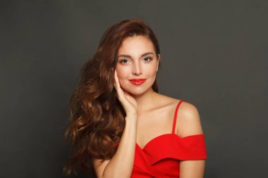 Siyah arka planda uzun saçlı ve makyajlı şık bir kadın. Kıvırcık saçlı, güzel bir kadın.