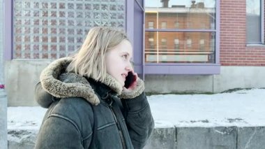 Sokakta cep telefonuyla konuşan genç bir kadının portresi.