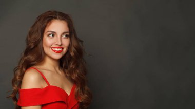 Moda makyajlı neşeli esmer kadın ve kahverengi kıvırcık saçlı, dalgalı saçlı ve siyah arka planda kırmızı dudaklı.