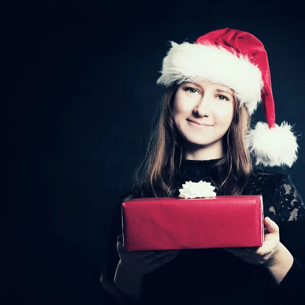 Mujer de Navidad en Santa Sombrero con caja de regalo roja sobre fondo oscuro — Foto de Stock