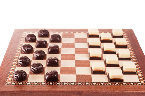 Schwarze und weiße Pralinen auf dem Schachbrett — Stockfoto