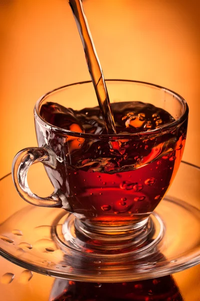 Té vertiendo en la taza de vidrio — Foto de Stock