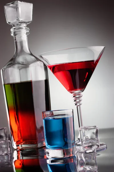 Carafe et verres remplis de boissons alcoolisées multicolores — Photo