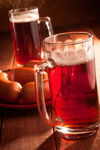 Two mugs filled with beer and hot sausages — Stock Photo, Image