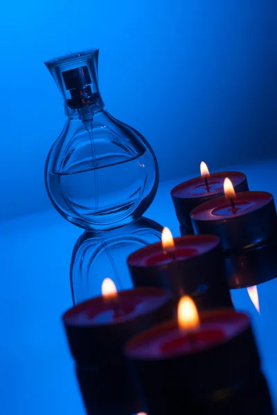Velas ardientes y frasco de perfume Imagen de archivo