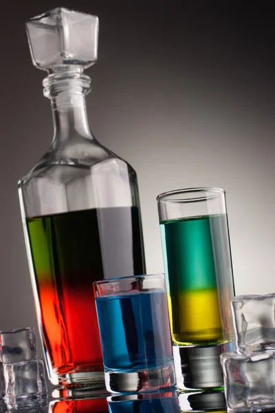 Carafe et verres remplis de boissons alcoolisées multicolores Images De Stock Libres De Droits