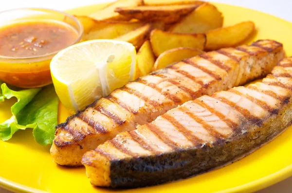 Filete de salmón a la parrilla con patatas y salsa en un plato amarillo —  Fotos de Stock