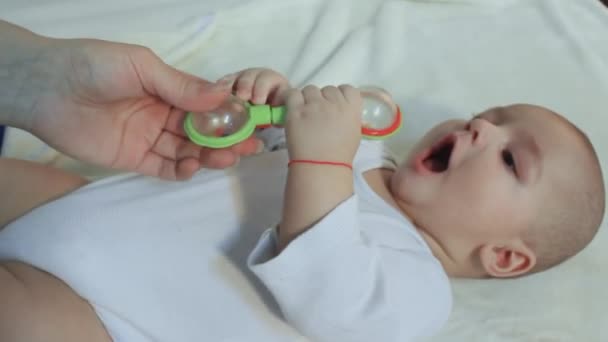 Niño está acostado sobre su espalda con un juguete — Vídeos de Stock